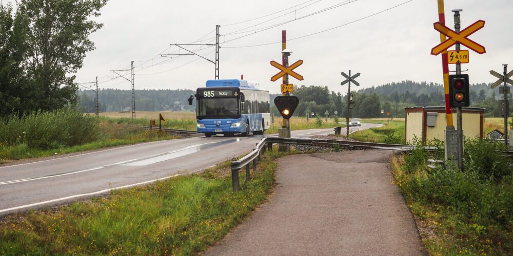 Linja-auto ajaa tasoristeyksen ylitse Suomessa maaseudulla.