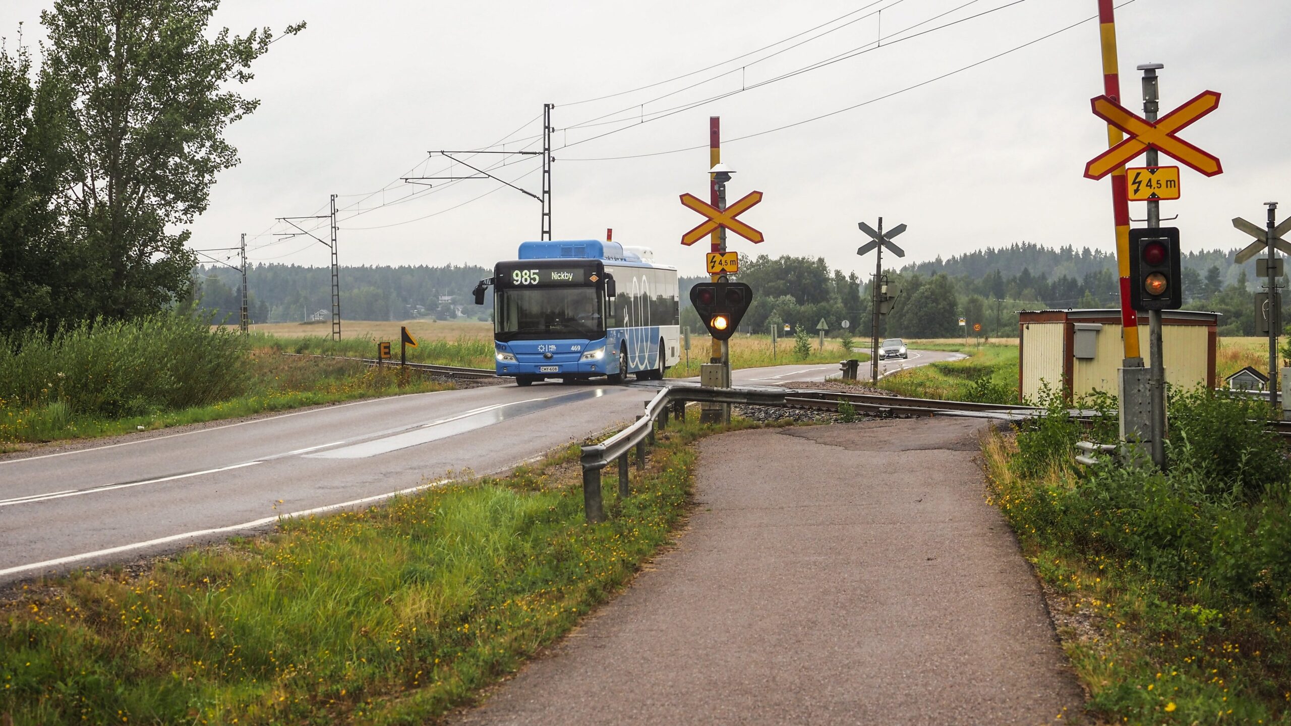 Linja-auto ajaa tasoristeyksen ylitse Suomessa maaseudulla.