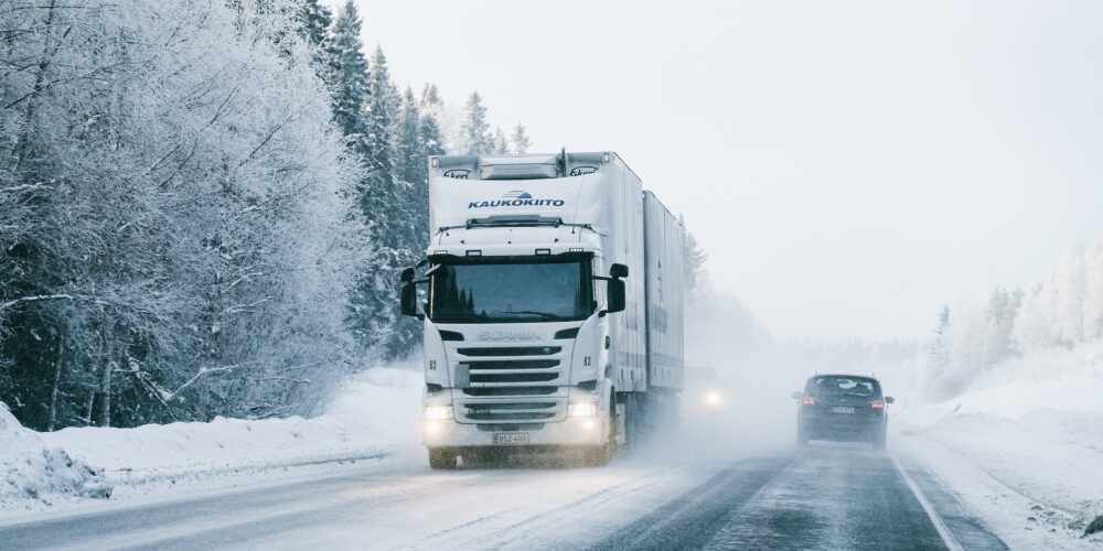 Rekka ja kaksi muuta ajoneuvoa liikkuvat talvisella tiellä Suomessa.
